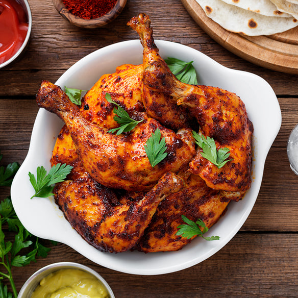 Whole roast chicken prepared with Indian spices made in a glass baking dish or on rotisserie.